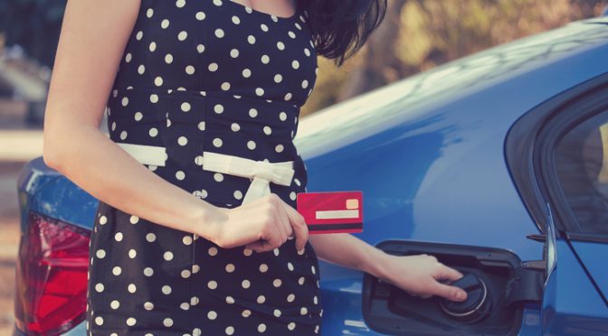 Closeup of a woman with credit card opening fuel tank of her new car